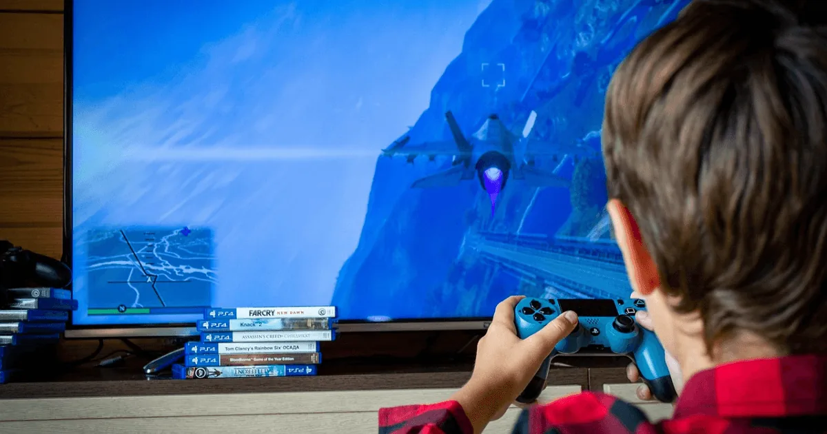 Criança jogando videogame em frente à TV, ilustrando o tema tempo de tela e desenvolvimento infantil